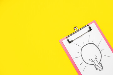 Clipboard with drawn light bulb on yellow background. Insight concept