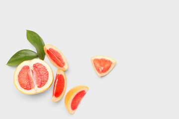 Pieces of ripe grapefruit and plant leaves on white background