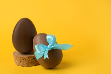 Tasty chocolate eggs on orange background. Space for text
