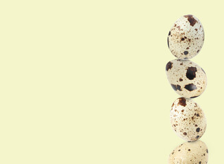 Stacked speckled quail eggs on light beige background. Space for text