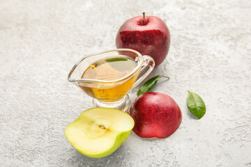 Gravy boat with fresh apple cider vinegar and fruits on white grunge background