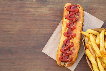Fresh tasty hot dog and french fries on wooden table, flat lay. Space for text