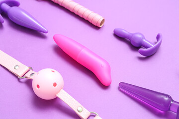 Different sex toys on purple background, closeup
