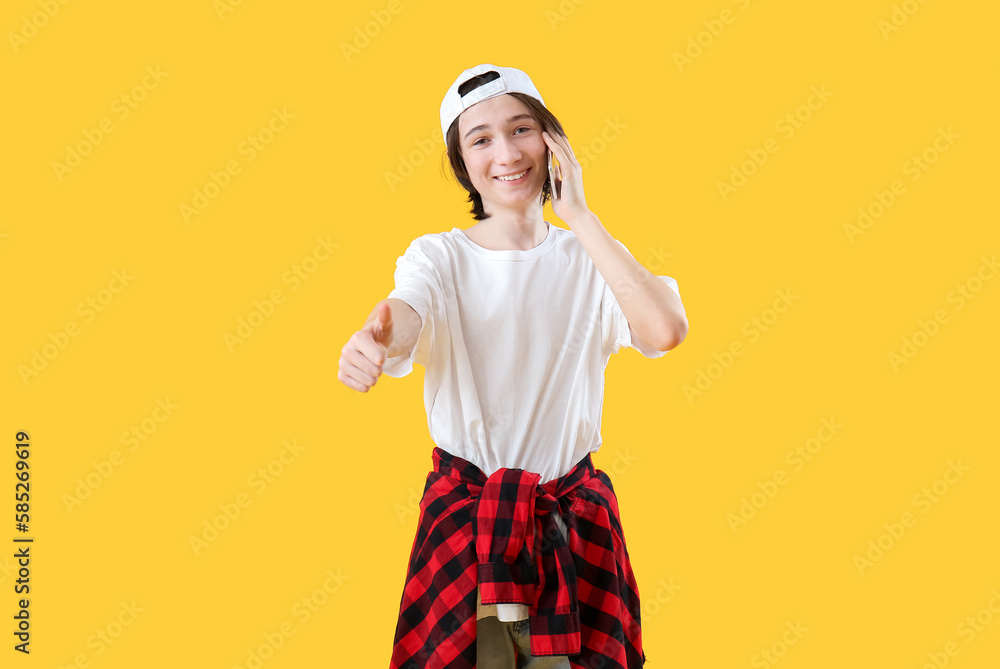 Canvas Prints Cool teenage boy talking by mobile phone on yellow background