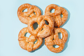 Tasty pretzels with sesame seeds on color background