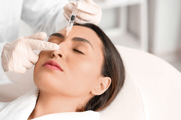 Fototapeta premium Young woman receiving filler injection in beauty salon