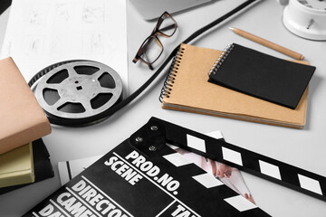 Notebooks with film reel and movie clapper on grey background, closeup