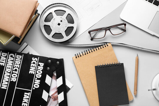 Notebooks with film reel and movie clapper on grey background