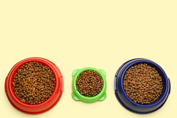 Different bowls with dry pet food on color background