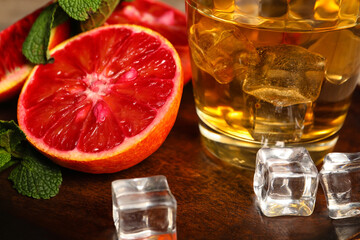 Glass of rum with ice, mint and Sicilian orange on table, closeup