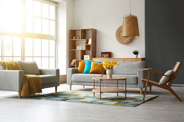 Interior of stylish living room with cozy sofa, armchairs and flower vase on coffee table