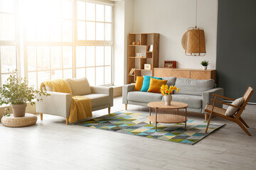 Interior of stylish living room with cozy sofa, armchairs and flower vase on coffee table