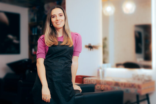 Happy Hairdresser Standing Next to an Empty Chair in a Salon. Smiling coiffeur employee waiting for a new client 
