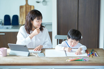 部屋で仕事をする母親と、お絵描きをする子供