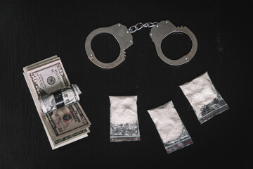 narcotic powder in bag of money and handcuffs on a black background of the table. The concept of...