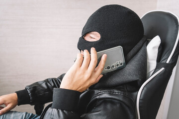 Robber making phone gesture. concept of telephone terrorism and fraud. A masked man makes a phone...
