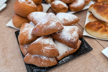 sweet pies with powdered sugar on the table or counter in the store.