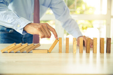 Close-up hand prevent wooden block not falling domino concepts of financial risk management and...