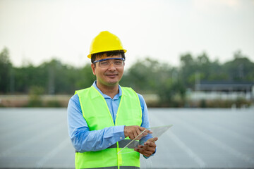Fototapeta premium Professional man engineer looking away with pleasure smile while working at ecological green field with solar panels. Photovoltaic power station concept