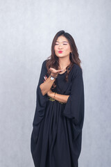 Asian chinese muslim headscarf hijab woman greeting ramadan fasting eid al fitr and eid al adha on white background. smiling expression of girl hand blowing love to you