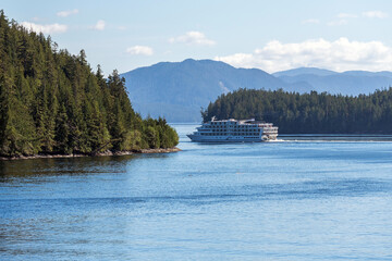 Cruise ship in between pine tree forest islands of the Inside Passage between Prince Rupert and Port Hardy, Vancouver Island, BC, Canada.