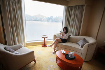 woman take a break and reading at home with Victoria harbour city view in Hong Kong
