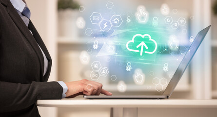 Hands working on laptop with digital icons