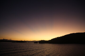 The sky turns into a canvas of warm hues as the sun emerges from the horizon, casting a golden trail on the rippling waves of the ocean.