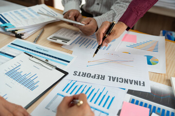 A group of Asian businessmen are brainstorming to analyze financial reporting situations. Calculate your investments with this calculator, income, tax and accounting from data graphs at your desk.