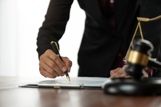 Female lawyer or legal counsel sitting at desk reading and reviewing data in file folder, legal book in accordance with the principles of jurisprudence to study and find information.