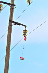 Sneakers hang on a high-voltage wire on a spring day