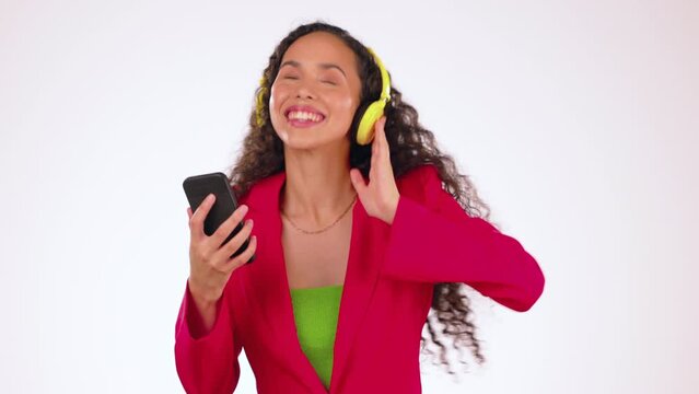 Black woman with smartphone, dancing to music with headphones and listening to radio on studio background. Fun, rhythm and dance with young female, mockup space and freedom with technology and energy