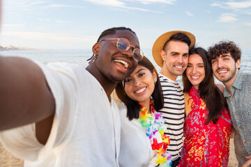 Group of happy, multiracial friends looking at camera take selfie together outdoors in the beach. Summer party.