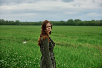 portrait of a beautiful, red-haired woman standing in a field in spring. Rainy weather, unity with nature