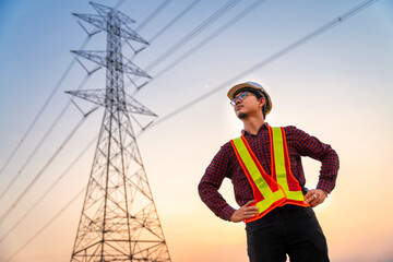 Handsome asian electrical engineer standing at high voltage pylon, Electricity generation concept.