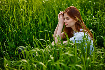 sad woman sitting in tall green grass on a sunny day