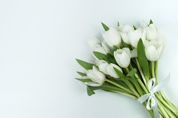 Liegender Blumenstrauß aus weißen Tulpen mit weißer Schleife rechts im Bild, weißer...