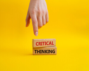 Critical thinking symbol. Wooden blocks with words Critical thinking. Businessman hand. Beautiful yellow background. Business and Critical thinking concept. Copy space.