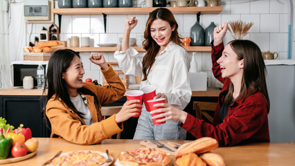 Group of friends clinking glass of beverage and eating italian p