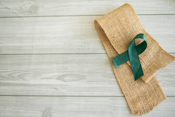 A Green ribbon on a jute mat, Concept related to medical awareness Selective focus