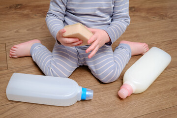 Toddler baby plays with household chemicals and detergent from the closet. Child boy with detergent...
