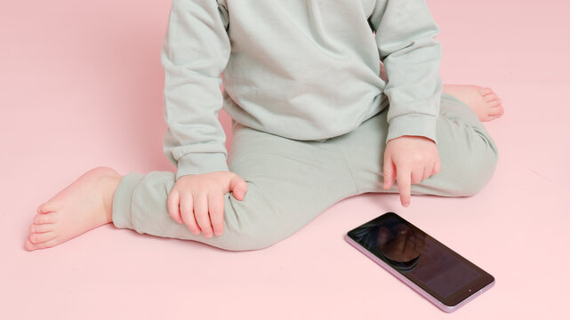 Happy Toddler Baby With Mobile Phone On Studio Pink Background. Child Boy Holding A Smartphone In His Hands. Kid Age One Year Eight Months