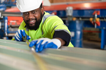 Portrait African American engineer man checking metal with tape measure at metal sheet factory	