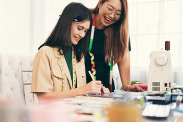 Happy beautiful Asia woman fashion designer clothes working with team in own dressmaking studio or boutique	