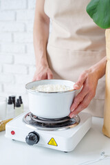 Woman making decorative aroma candles from soy wax
