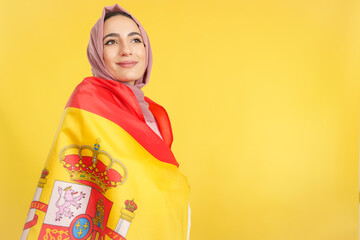 Dreamy muslim woman wrapped by a spanish national flag