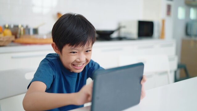Asian little boy play games on tablet at home on weekends. The children addicted to games concept