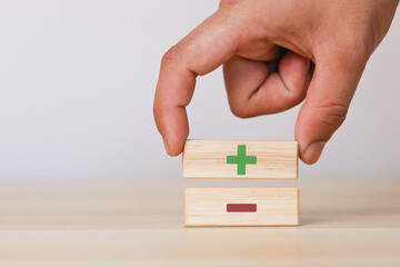 Wooden blocks showing plus and minus signs. The concept of antithesis. Decision making. Positive or...