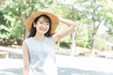 帽子を被って紫外線対策するアジア人女性（日焼け止め・UVケア）
