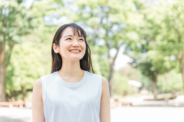 緑の中で笑う若い日本人女性（環境・美白・SDGs/笑顔）
